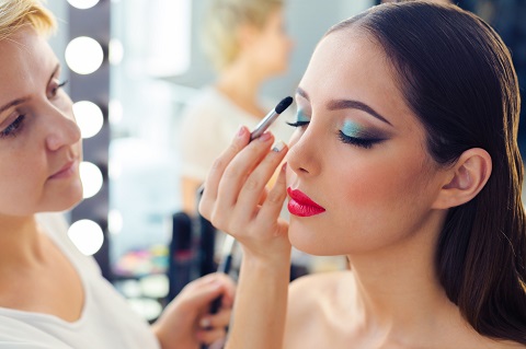 make up artist doing professional make up of young woman